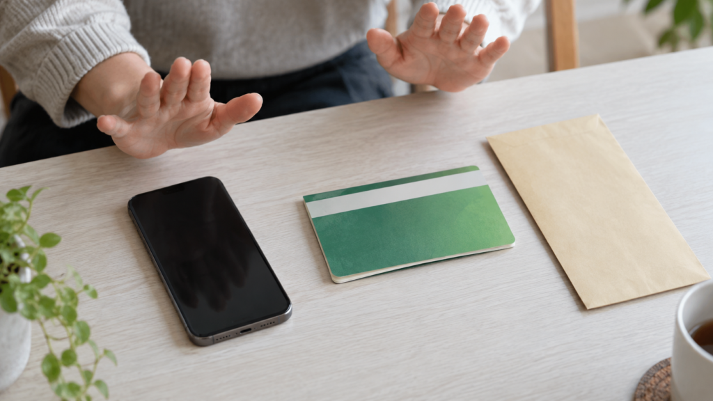 スマートフォンから手を離して投資の案内を確かめる人の手元