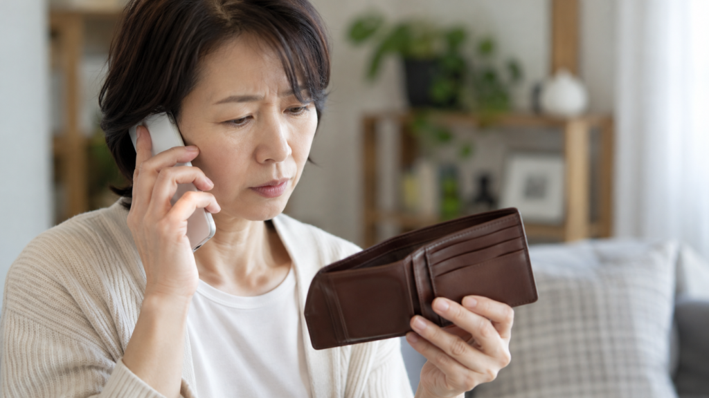 財布を確かめながら電話で紛失を相談する女性