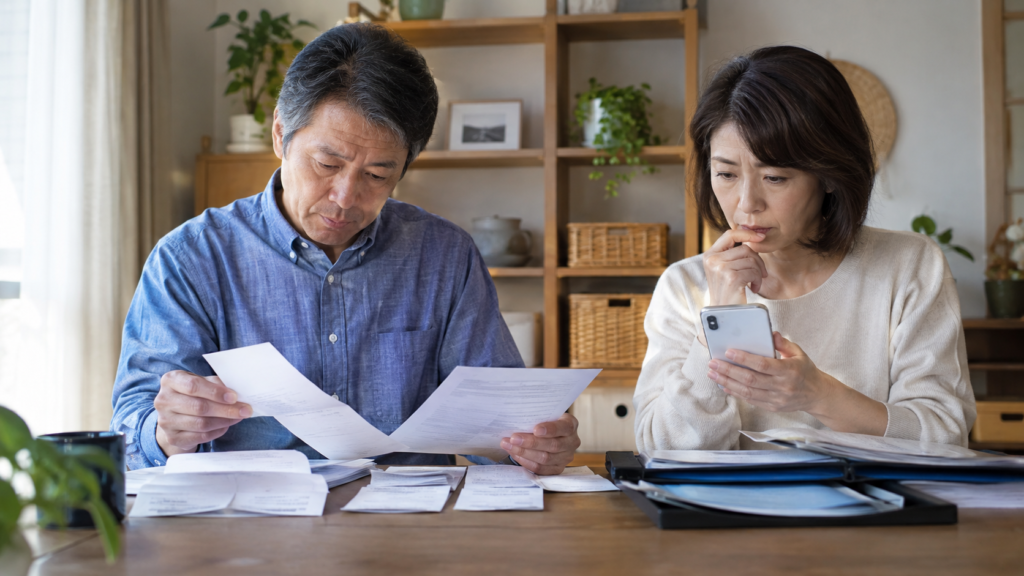 家計書類を分類しスマートフォンで確認する夫婦