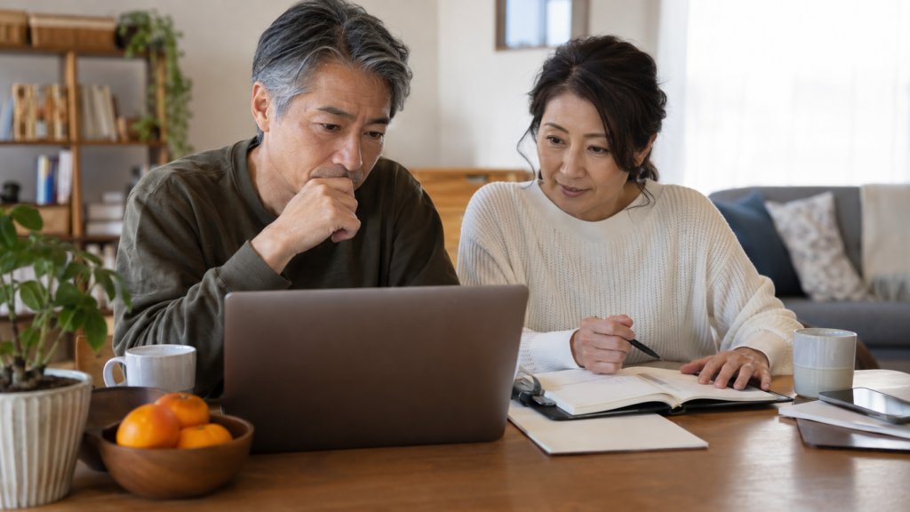 パソコンと手帳で返済方法を比較する夫婦